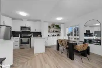 Kitchen featuring white cabinets, crown molding, decorative backsplash, appliances with stainless steel finishes, and light hardwood / wood-style floors